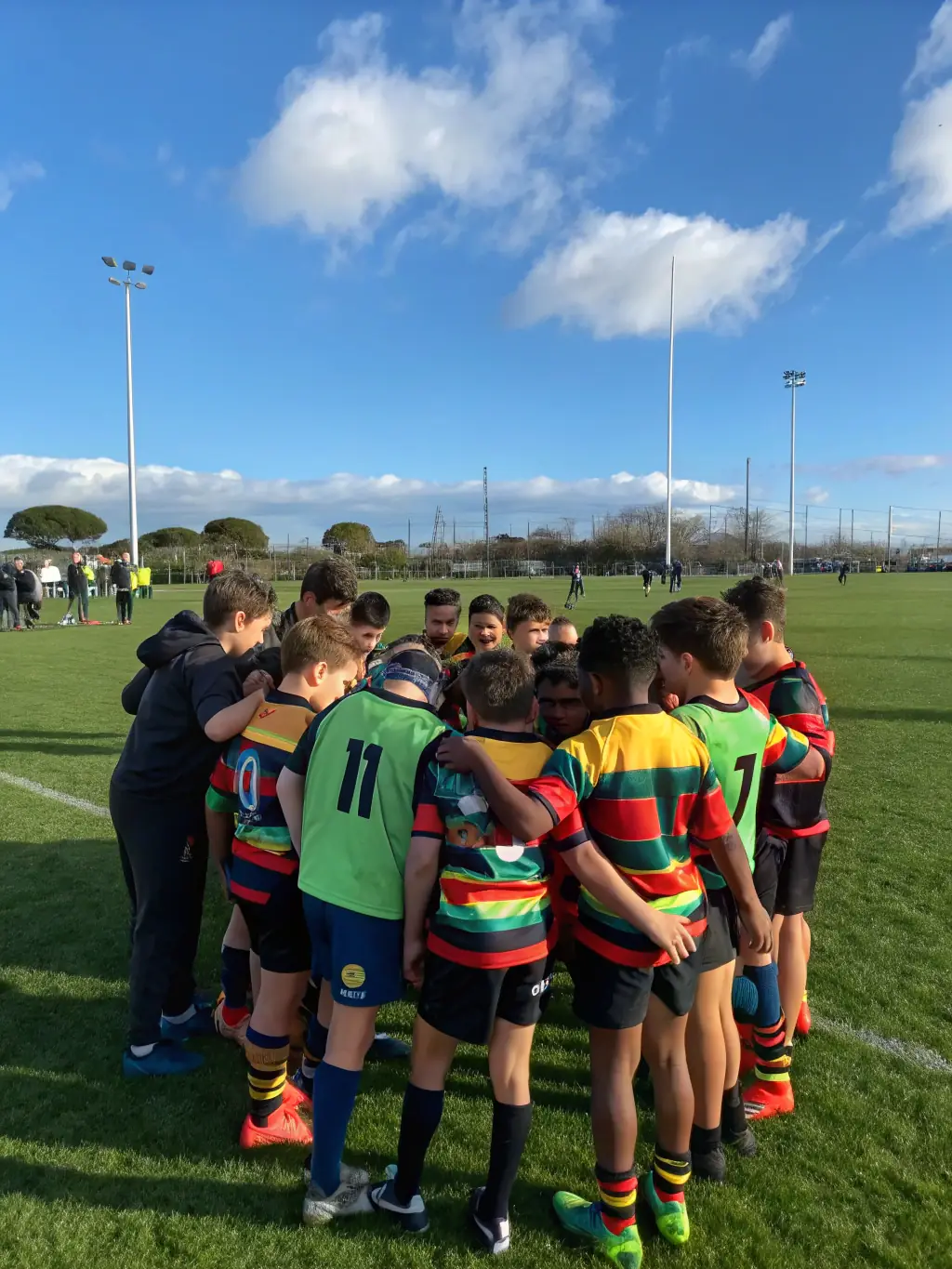 A diverse group of teenagers engaged in a rugby match, showcasing teamwork and sportsmanship, with coaches providing guidance and encouragement from the sidelines.